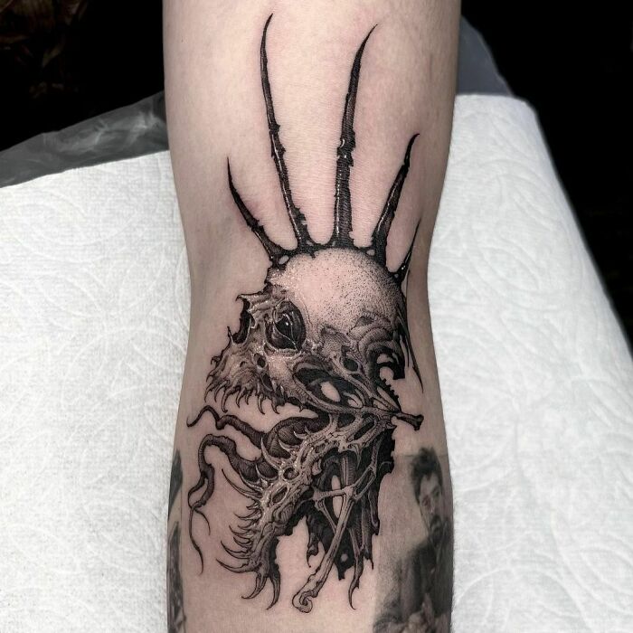 Gothic tattoo depicting a skeletal creature with spikes on an arm.