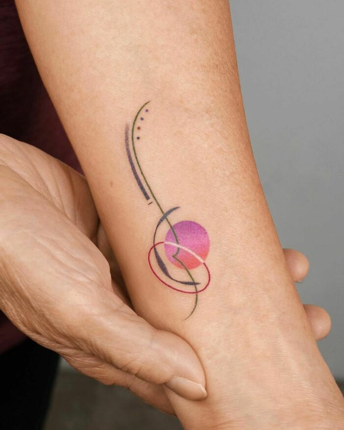 Abstract tattoo design featuring curves and geometric shapes on a person's forearm.