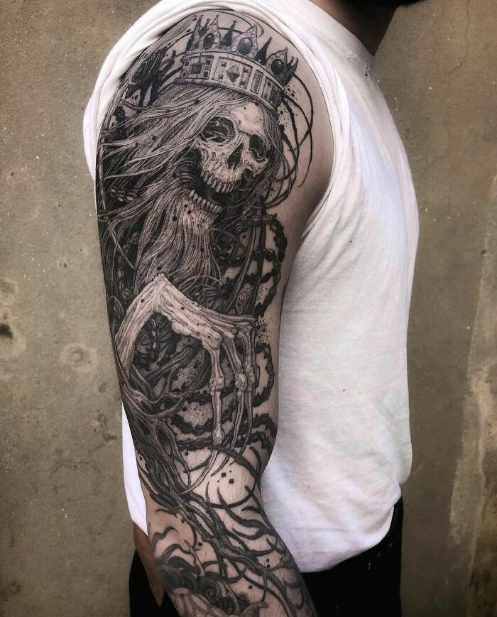 Detailed Bloodborne video game tattoo of a skeletal figure wearing a crown on a person's arm.