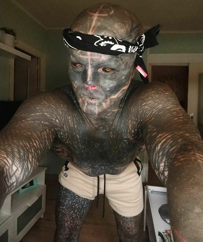 Man with extensive body modifications, including tattoos, wearing a bandana. Man with extensive body modifications, including tattoos, wearing a bandana.