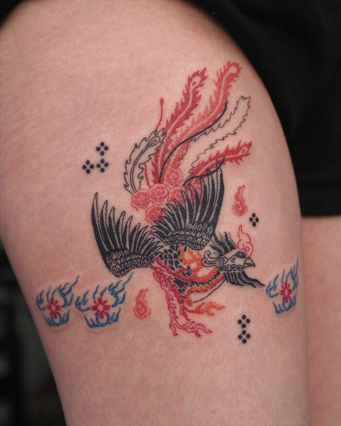 Colorful abstract tattoo of a mythical bird with flames, showcasing artistry and self-expression on skin.