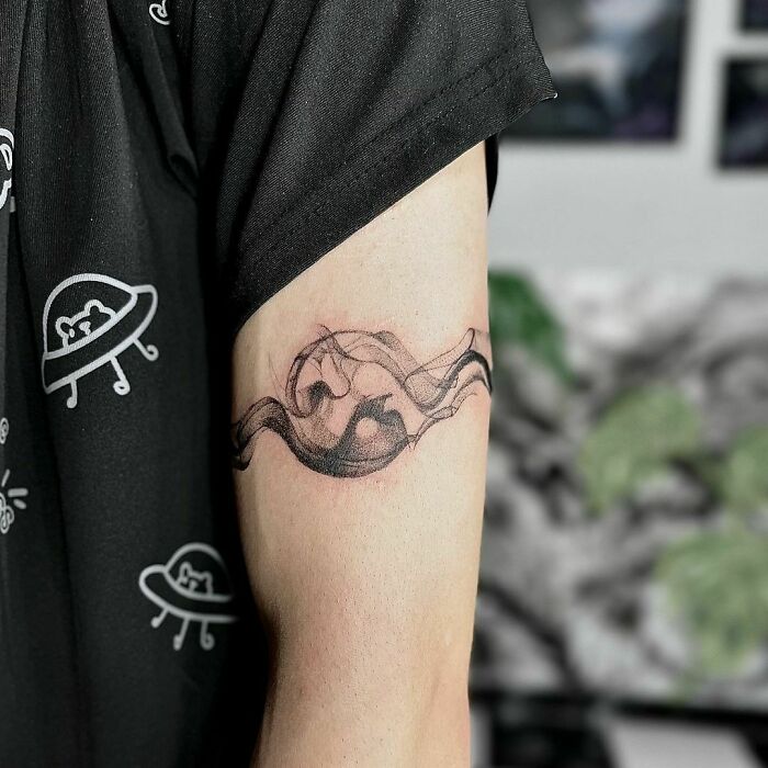 Abstract yin yang tattoo design on upper arm showcasing duality.