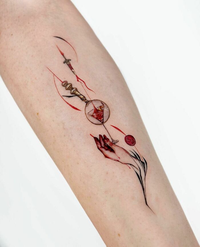Abstract tattoo with red and black geometric design on a forearm, showcasing artistry and self-expression.