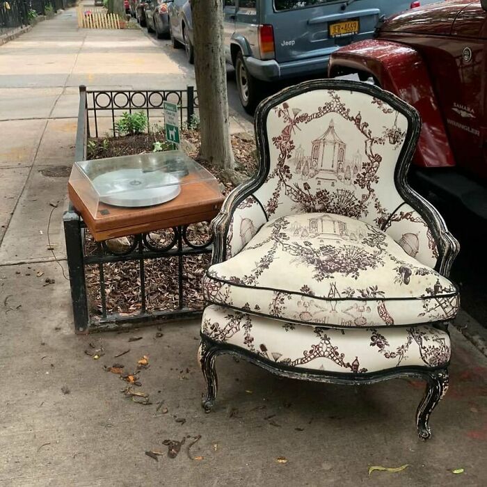Vintage patterned armchair and record player left on NYC sidewalk as surprising real treasures discarded on the street.