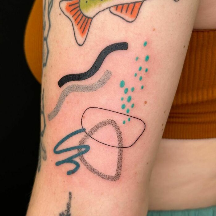 Colorful abstract tattoo design featuring wavy lines and dots on an arm.
