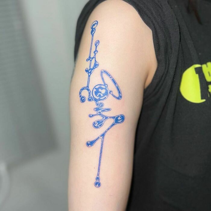 Blue abstract tattoo design on an arm, showcasing unique artistry and self-expression.