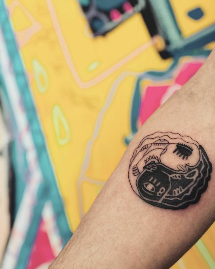 Yin Yang tattoo on arm, illustrating duality with abstract black and white design.