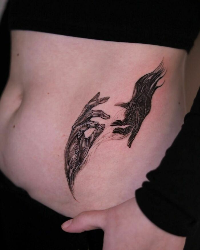 Abstract tattoo of artistic hands and flowing shapes on the side of a person's torso, showcasing creative self-expression.