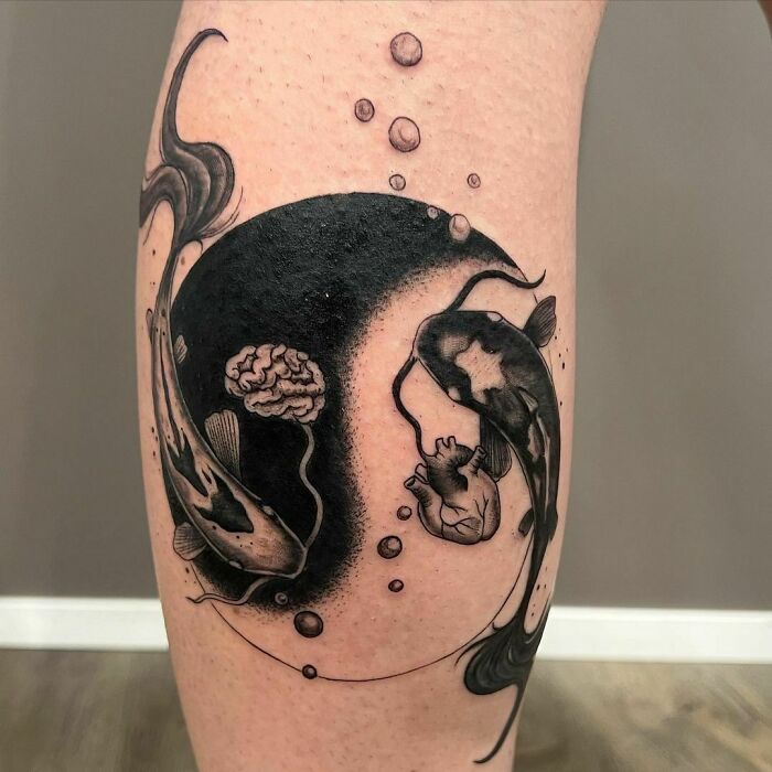 Yin Yang tattoo featuring koi fish and bubbles on a person's leg, symbolizing life's duality.