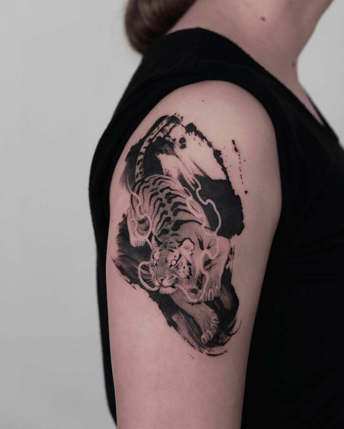 Abstract tattoo of a tiger on upper arm, blending artistic elements and self-expression.
