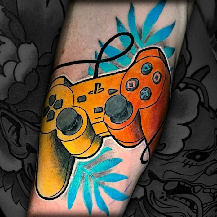 Game controller tattoo with bright colors on forearm, perfect for hardcore gamers.