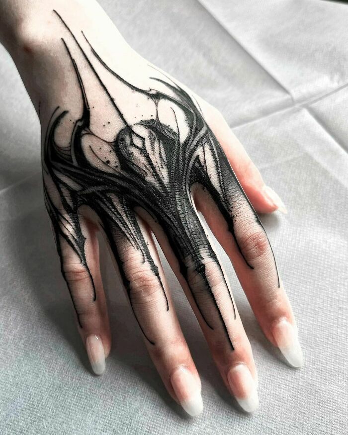 Close-up of a hand showcasing an intricate Gothic tattoo design in black ink.