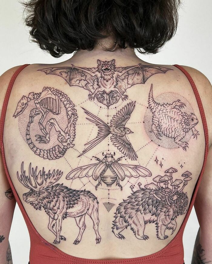 Intricate gothic tattoos featuring bats, birds, and animals on a person's back.