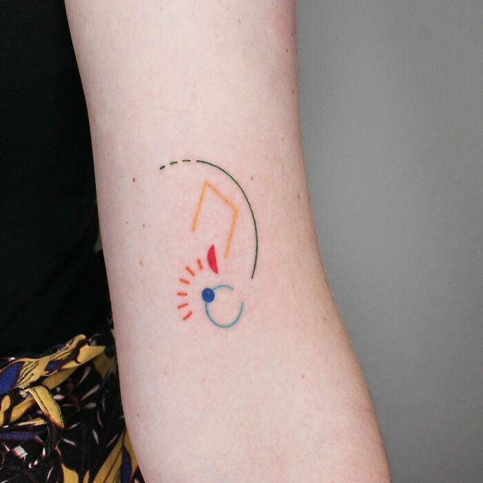 Abstract tattoo design on an arm featuring colorful geometric shapes and lines.