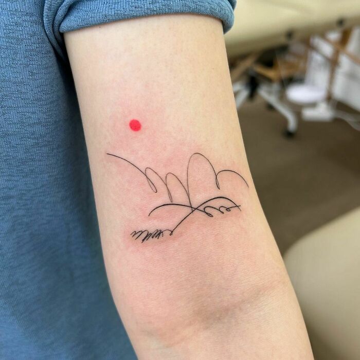 Abstract tattoo with delicate black line art and a red dot on the forearm, showcasing artistry and self-expression.