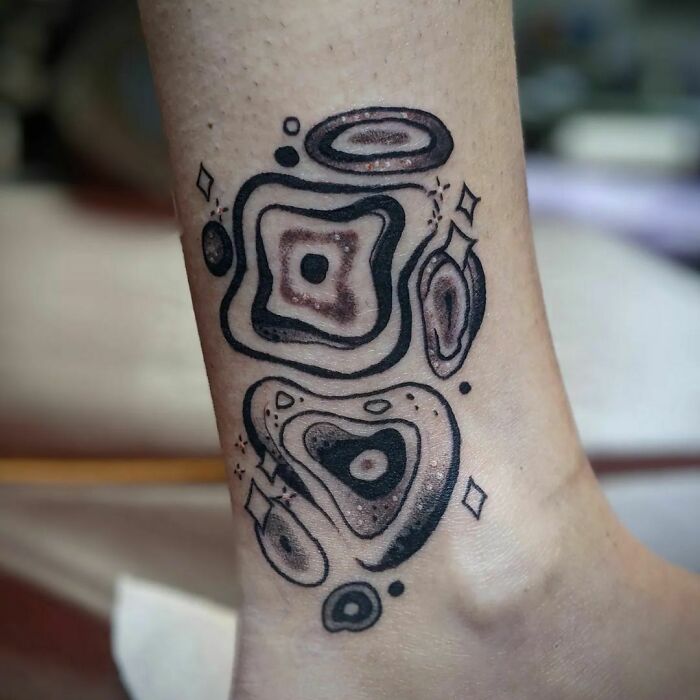 Abstract tattoo on ankle featuring geometric and fluid designs, showcasing self-expression through artistry.