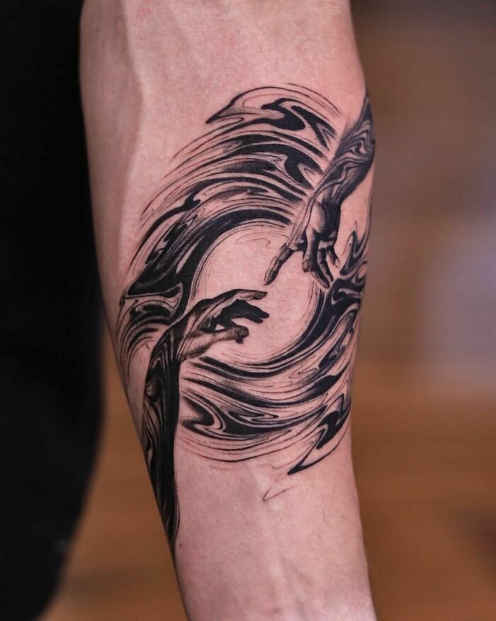 Abstract tattoo on arm featuring swirling patterns and hands, showcasing artistry and self-expression.