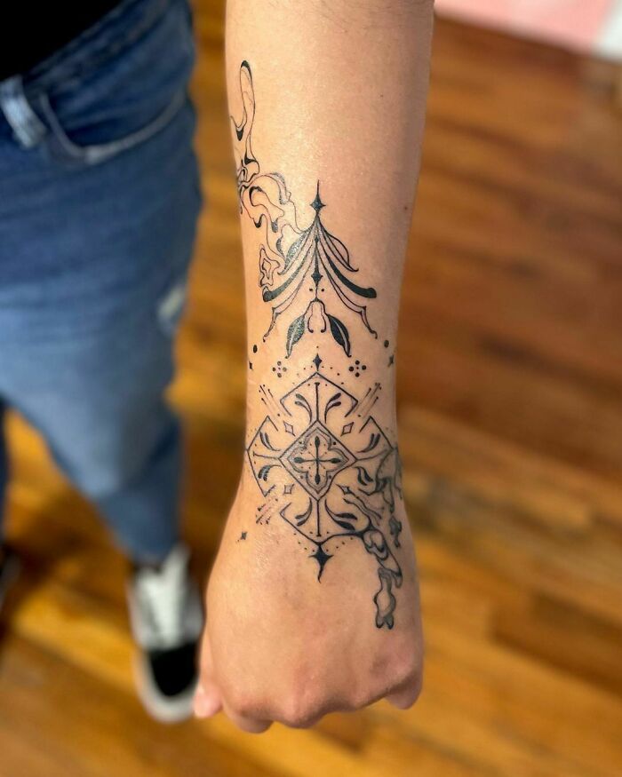Abstract tattoo design on forearm featuring intricate patterns in a unique artistic style.