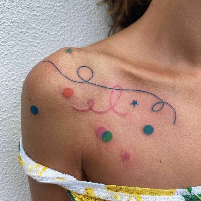 Abstract tattoo with colorful dots and lines on shoulder, symbolizing self-expression in art.