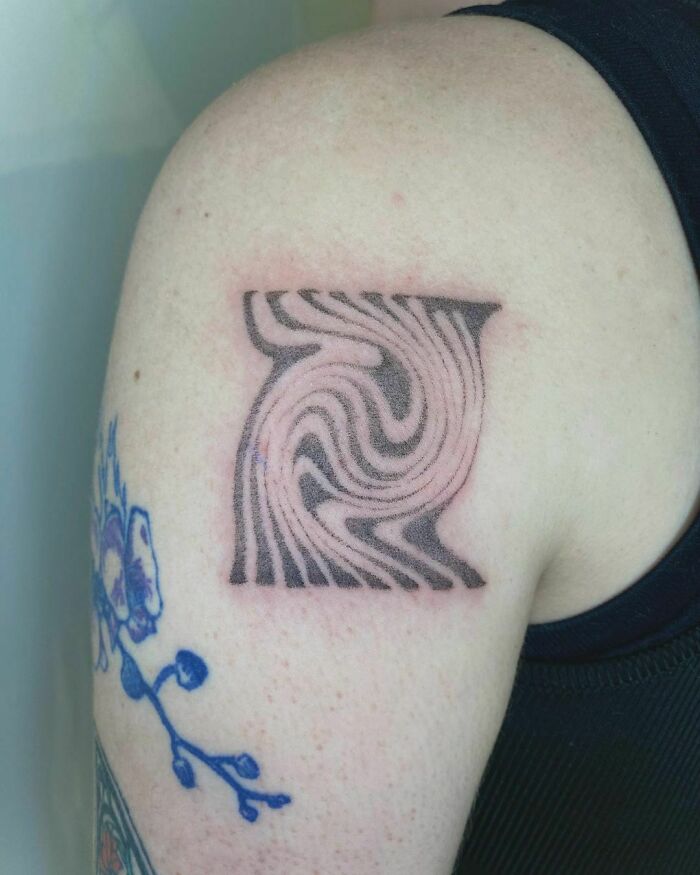 Abstract tattoo with swirling pattern on shoulder showcasing unique artistry and self-expression.