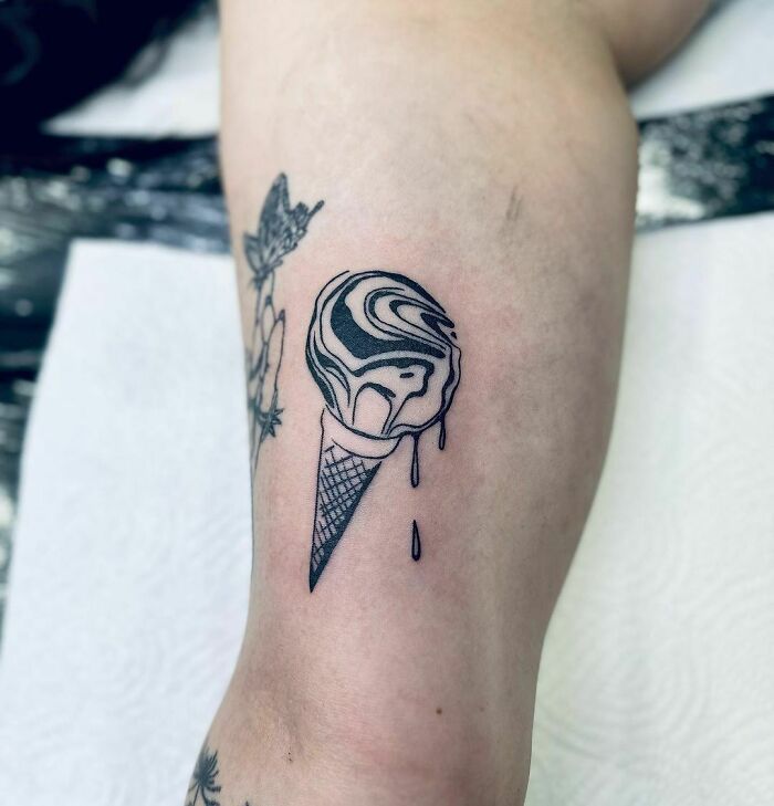 Abstract tattoo of a melting ice cream cone on a leg, showcasing creative self-expression.