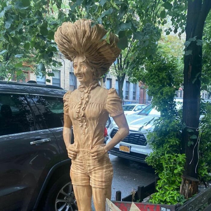 Wooden sculpture of a woman with large hair standing on a New York City sidewalk, a rare treasure discarded in NYC.