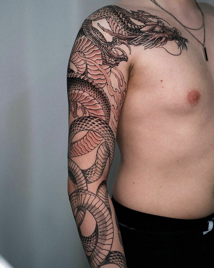 Man with an intricate snake tattoo covering his arm and shoulder.