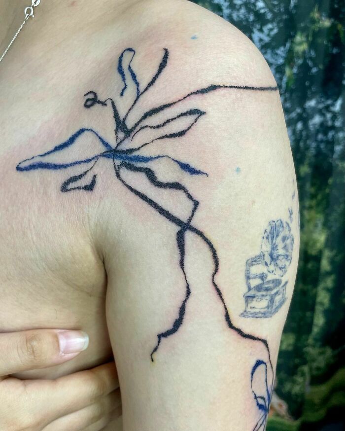 Abstract tattoo with flowing lines and shapes on upper arm, showcasing artistic self-expression.