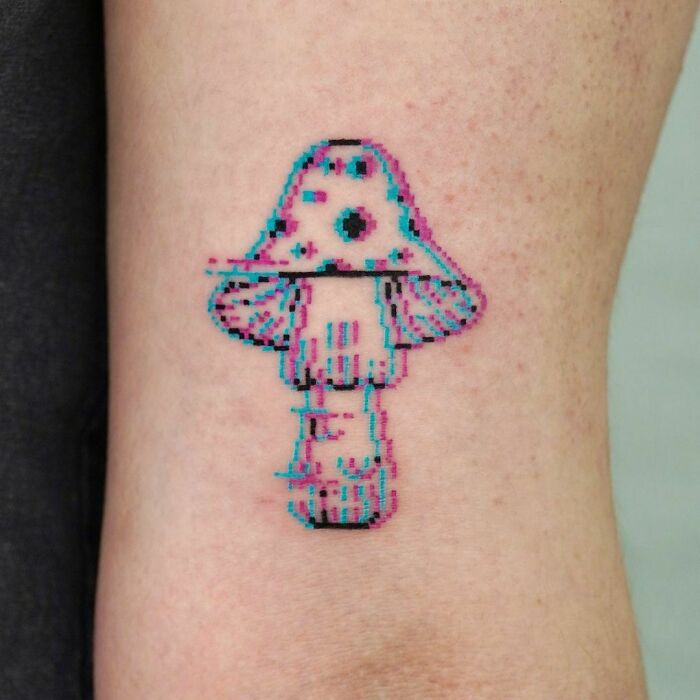 Pixelated mushroom tattoo on skin, inspired by video game designs.