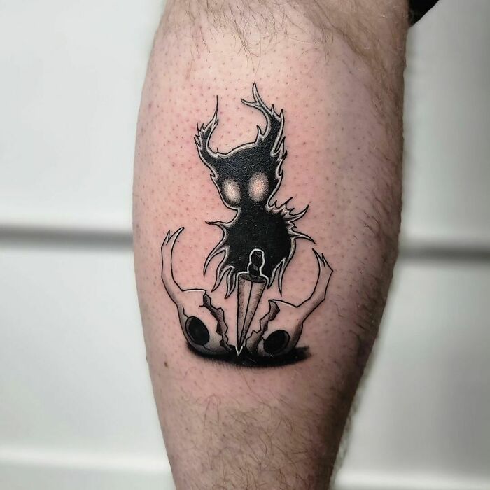 Hollow Knight video game tattoo featuring a dark figure with glowing eyes and a sword on a person's leg.