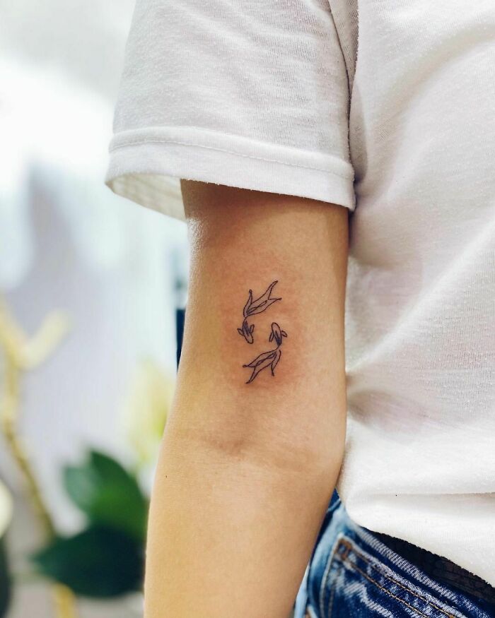Minimalist tattoo of fish on forearm represents mental health and healing.