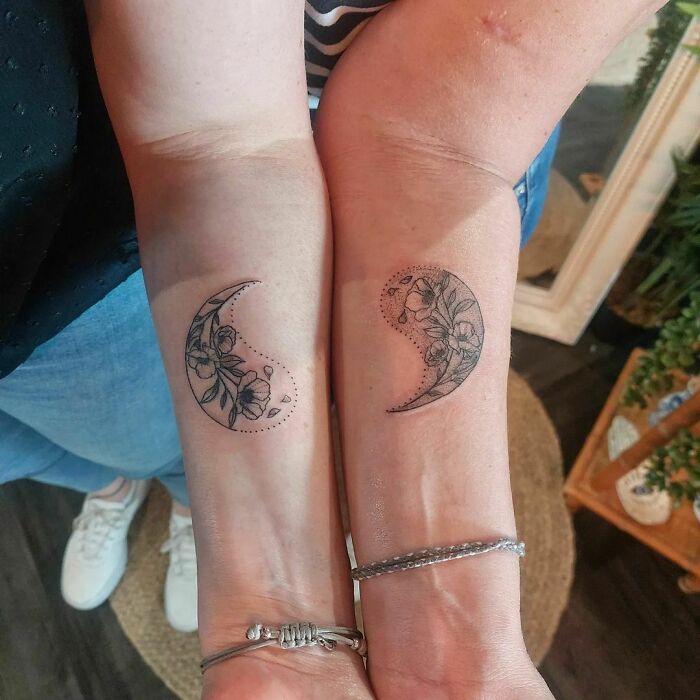 Matching floral Yin Yang tattoos on forearms, showcasing duality of life.