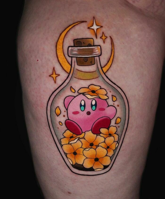 Video game tattoo featuring Kirby in a bottle with yellow flowers, crescent moon, and stars.