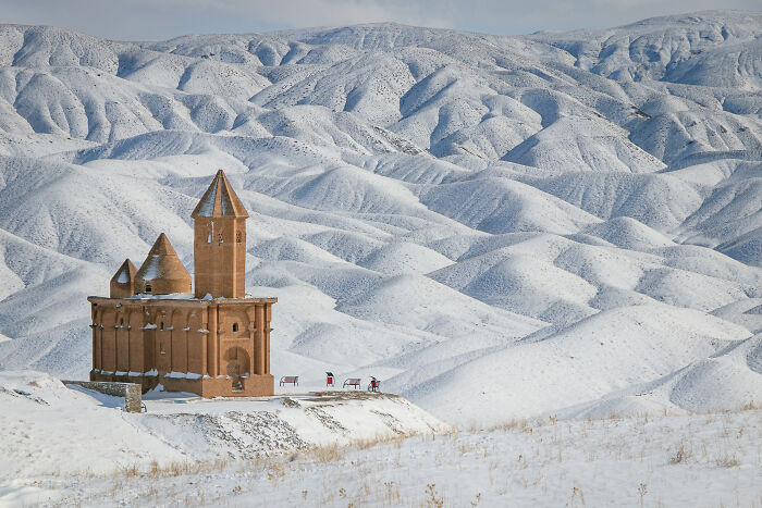 Historic brick church covered in snow with snowy hills in the background, featured in Wikimedia Commons best pictures.