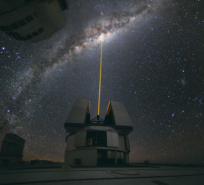 Telescope with laser beam pointing at Milky Way galaxy under a star-filled night sky, Wikimedia Commons best pictures.