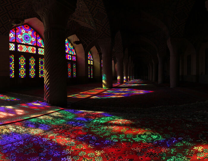Colorful stained glass windows casting vibrant patterns on the floor of a historic building, Wikimedia Commons photo.