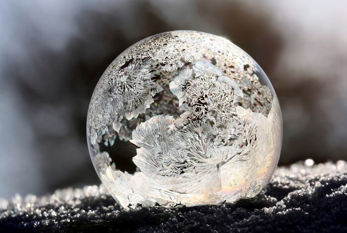 Frozen soap bubble with intricate ice crystal patterns resting on snow, one of the best pictures chosen by Wikimedia Commons community