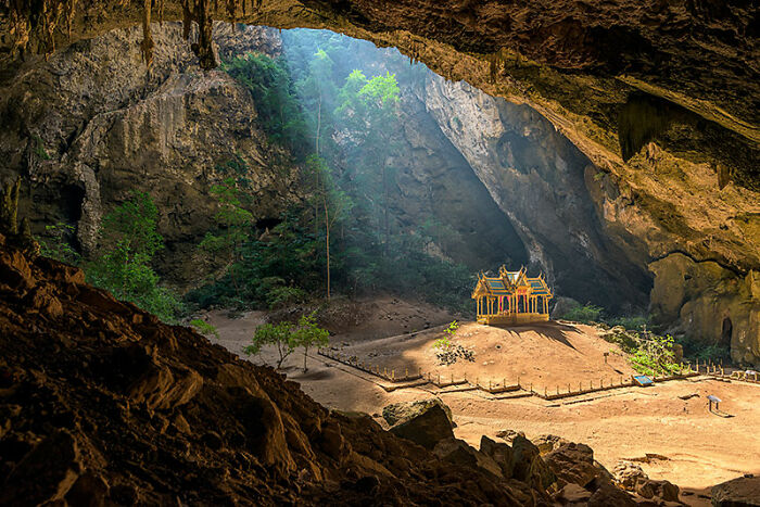 Sunlight illuminating a small temple inside a large cave, featured among the best pictures from 2006-2022 community selection.