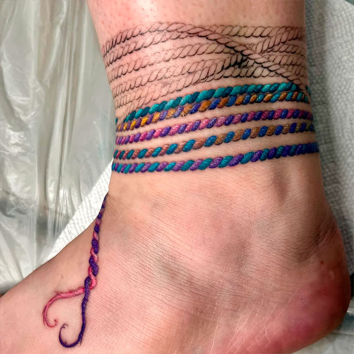 Colorful ankle tattoo design with braided patterns around the foot.