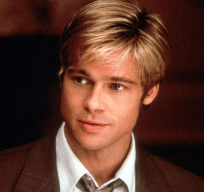Man with blonde hair in a striped shirt and tie, looking to the side.