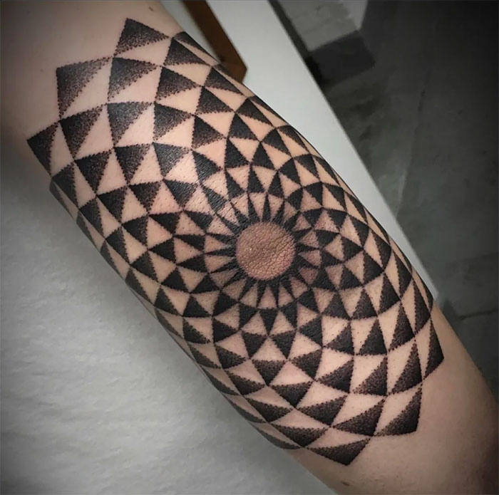 Geometric pattern elbow tattoo design with black and gray triangles.
