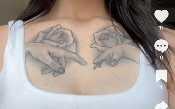 Woman with funny tattoo of hands reaching out, surrounded by roses, on chest.