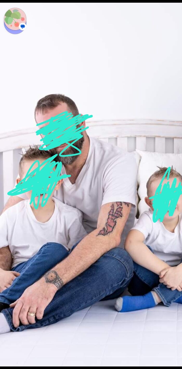 Man with funny tattoos on arm sitting on bed with two kids.