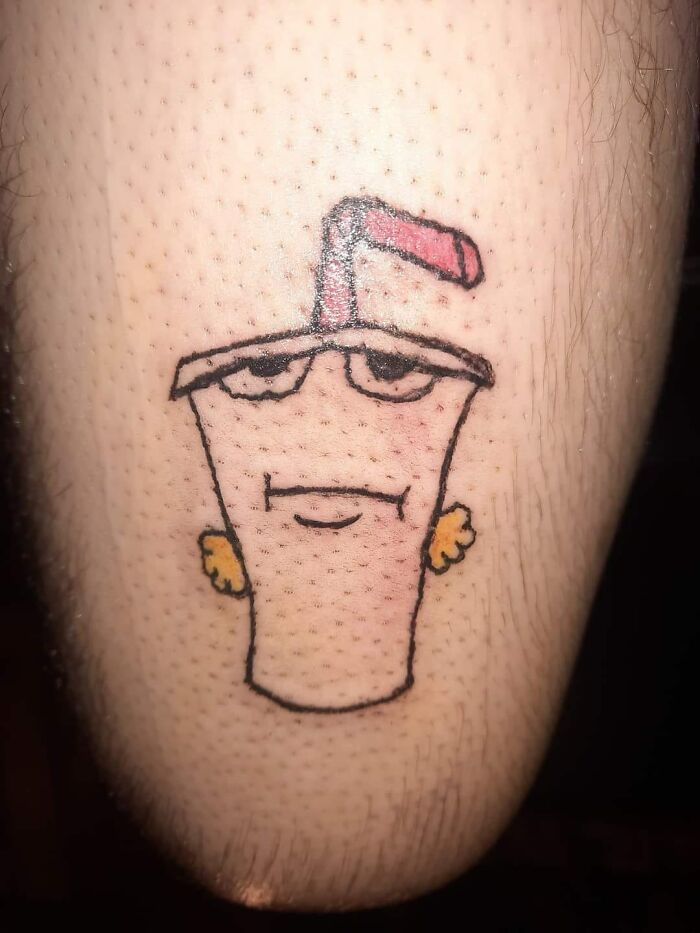 Amusing tattoo of a discontented drink cup with a straw on skin.