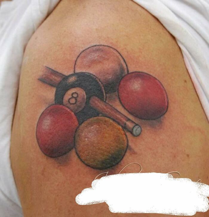 Tattoo of colorful billiard balls and a cue, featuring an 8-ball.