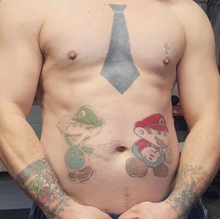 Funny tattoos of cartoon characters on a man's torso, featuring a necktie design on the chest.