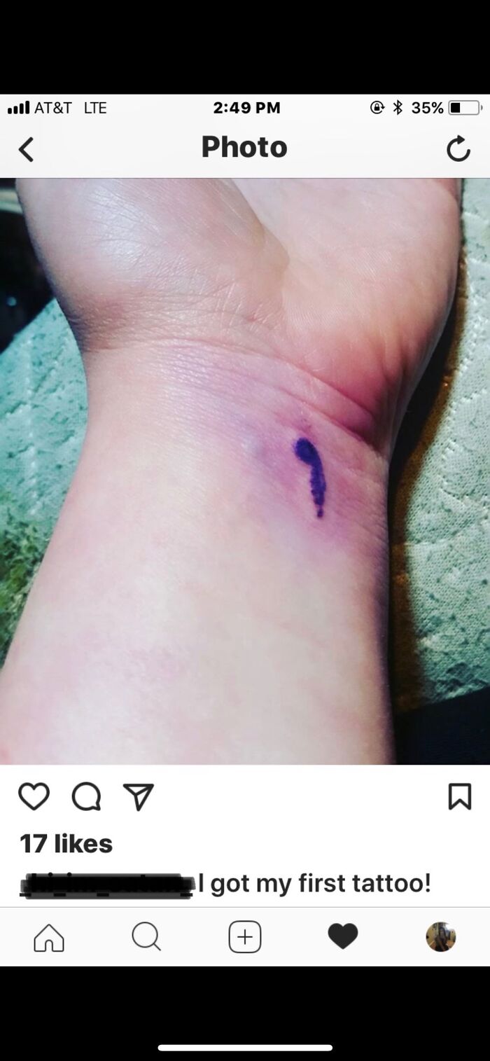 Close-up of a wrist with a small, simple tattoo resembling a semicolon.