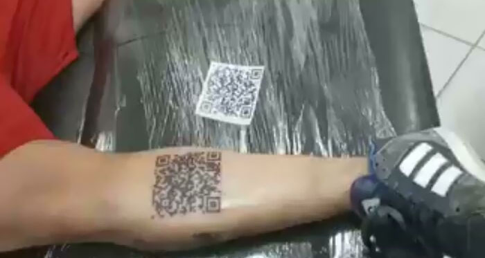 Arm with QR code tattoo being inked, highlighting permanent tattoo mistakes.