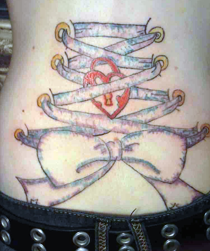 Corset tattoo with a bow and heart lock, illustrating mistakes made in getting inked.