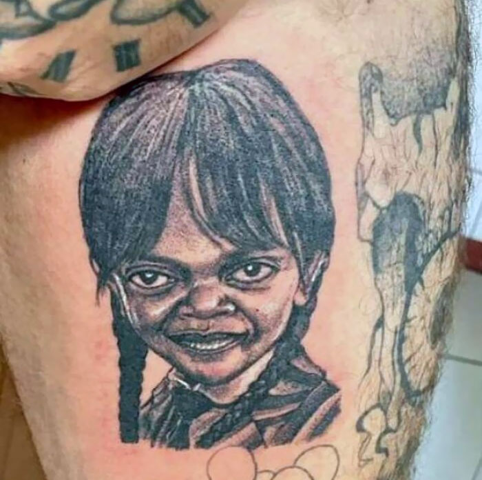 Tattoo of a child's face with distorted features on a person's thigh, illustrating common tattoo mistakes.